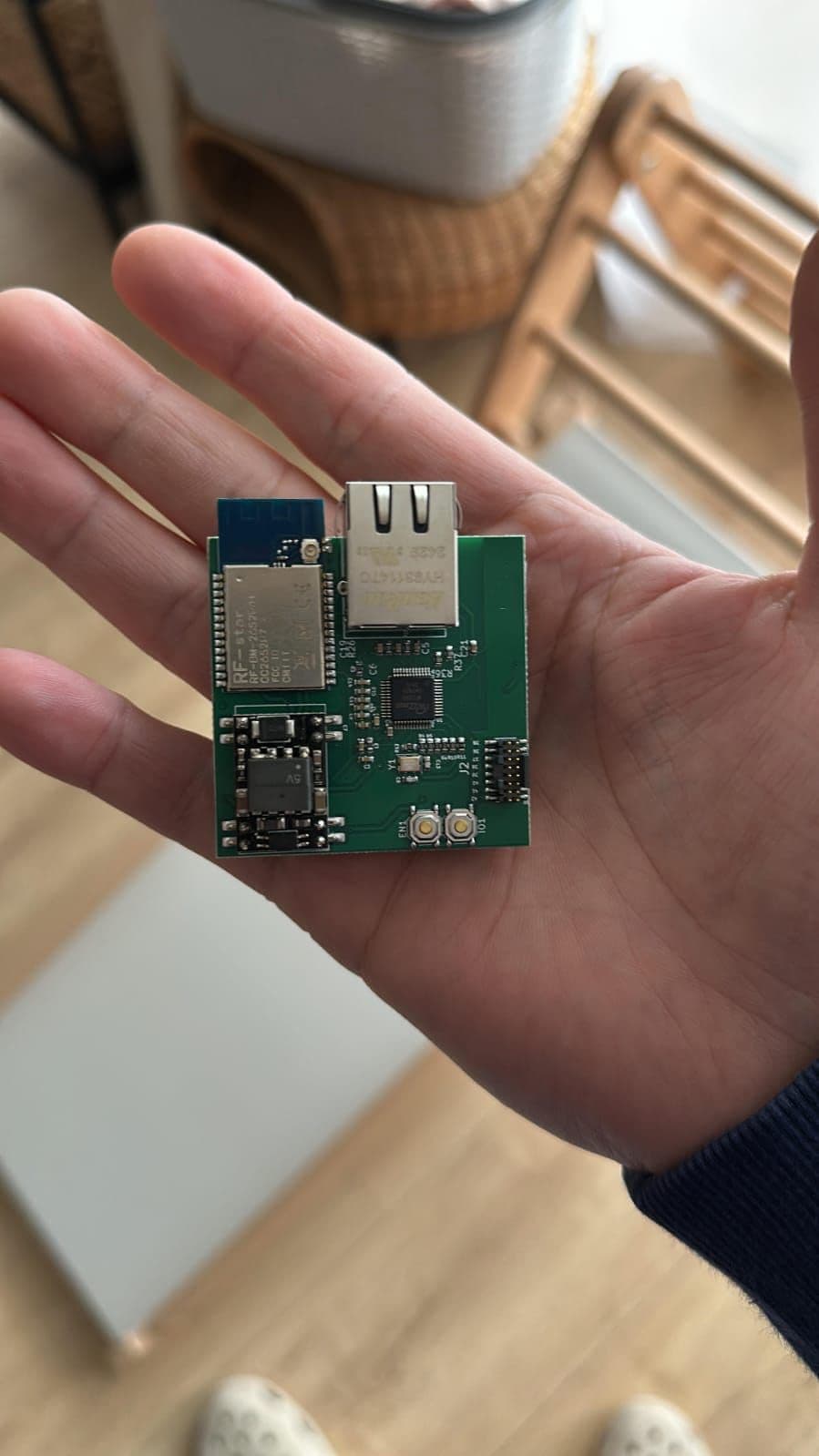 Assembled ESP32 PoE IoT gateway PCB held in a hand, showing the RJ45 Ethernet jack, wireless module, Ethernet controller and 5V power section